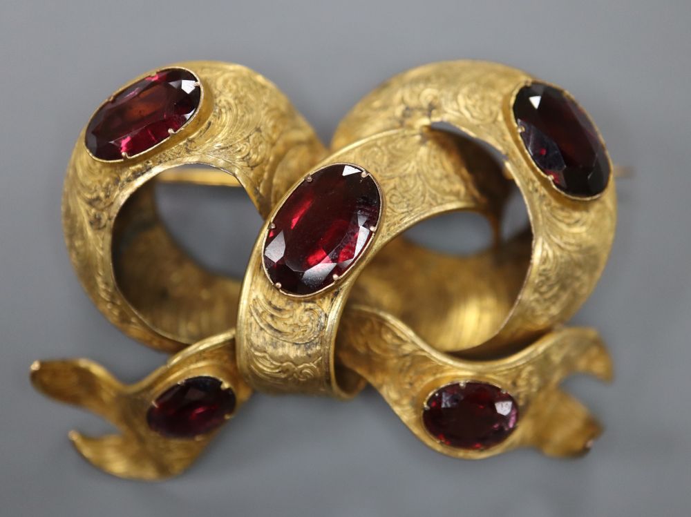 A Victorian yellow metal and five stone oval garnet set scroll mourning brooch,